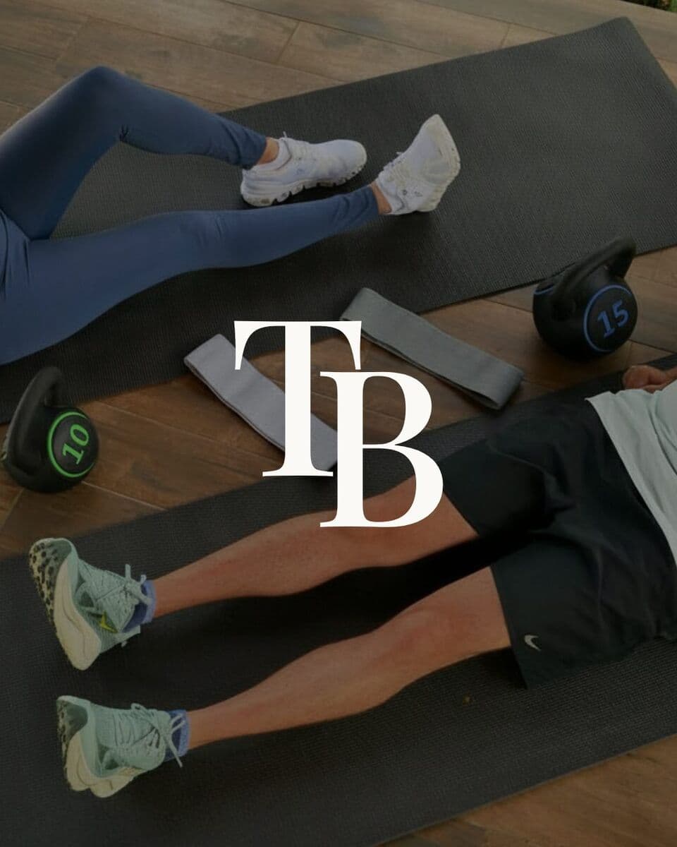 Two people training on mats with kettlebells and resistance bands